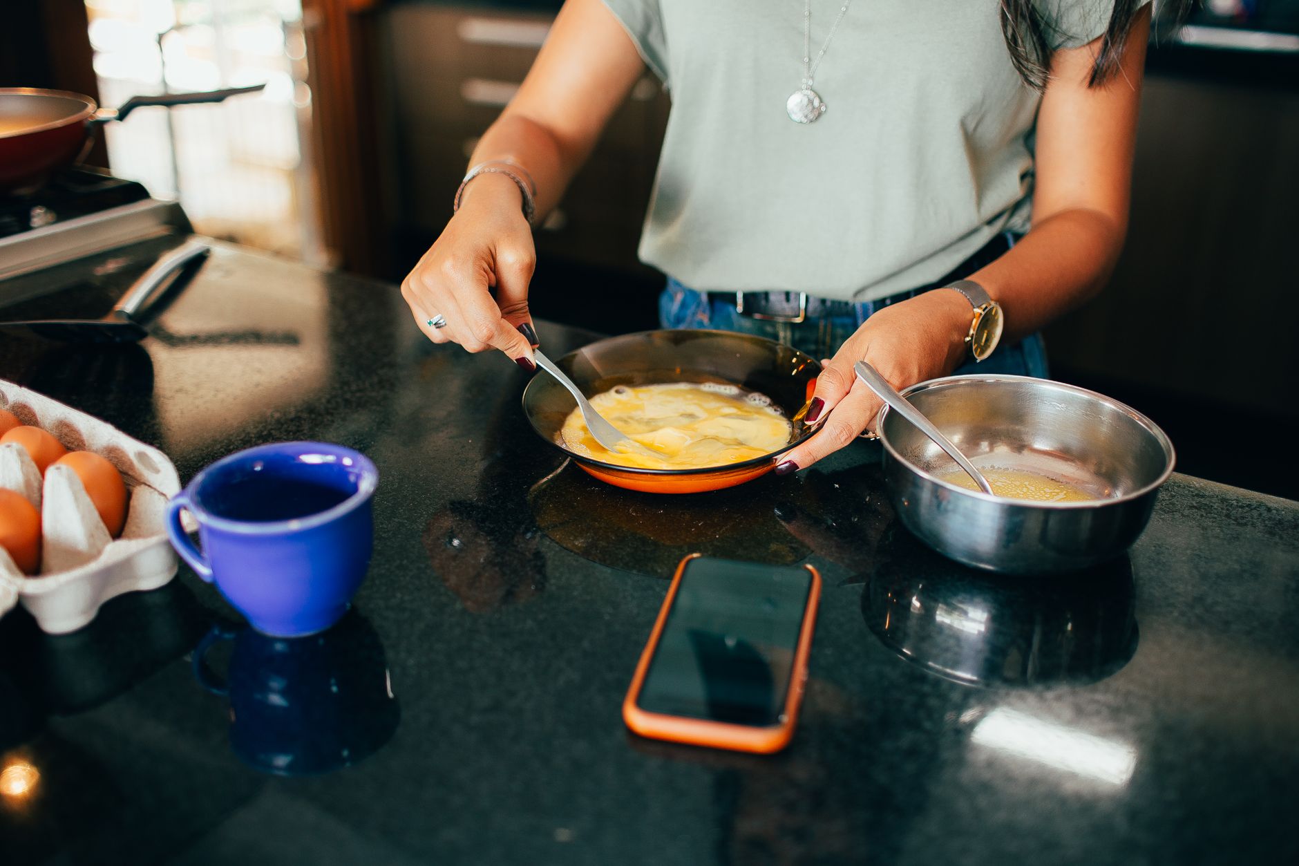 Woman beating eggs in a modern kitchen with various utensils around.