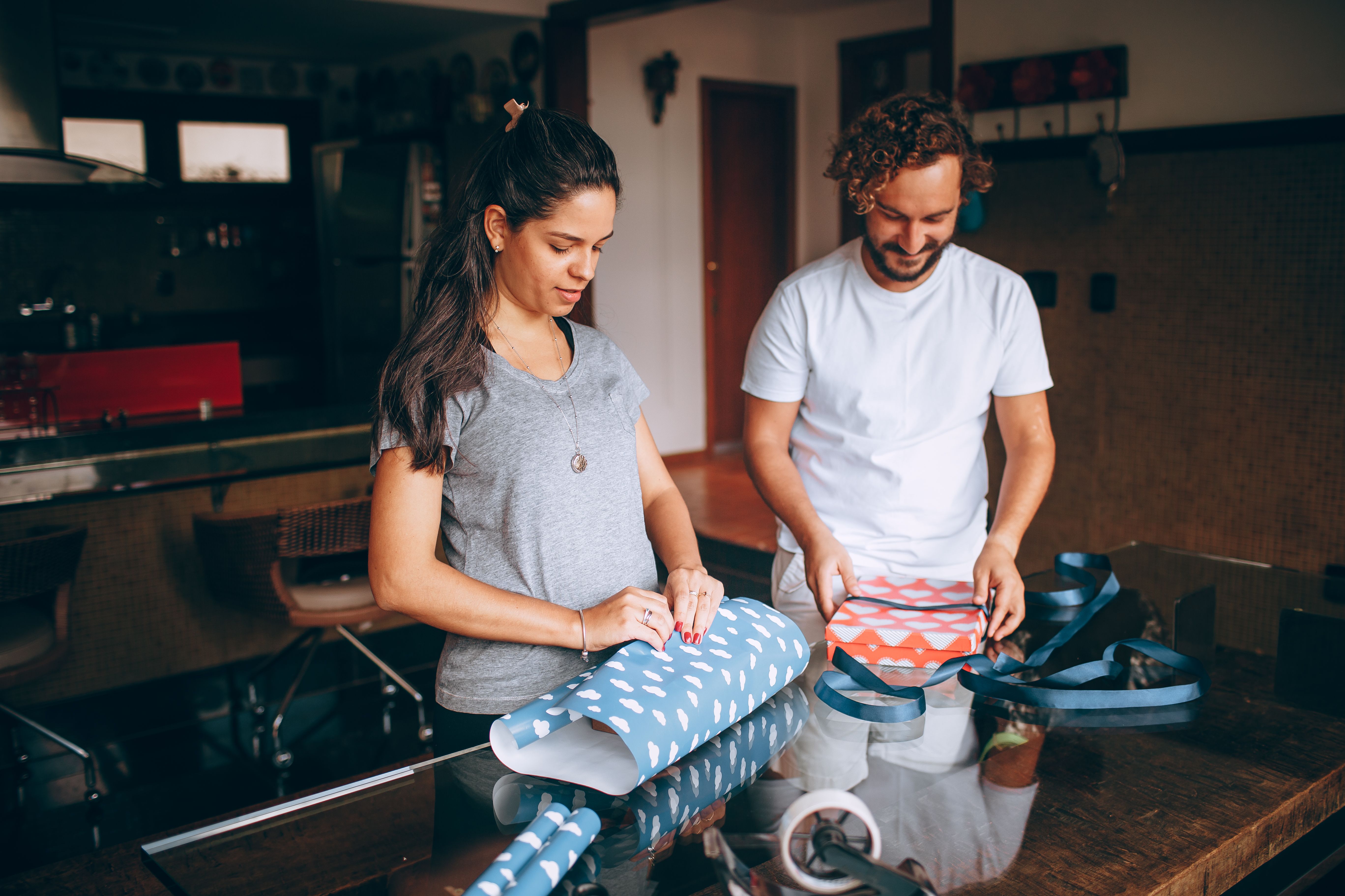 Dois jovens envoltos na preparação de presentes, representando criatividade e momentos de celebração em um ambiente doméstico.