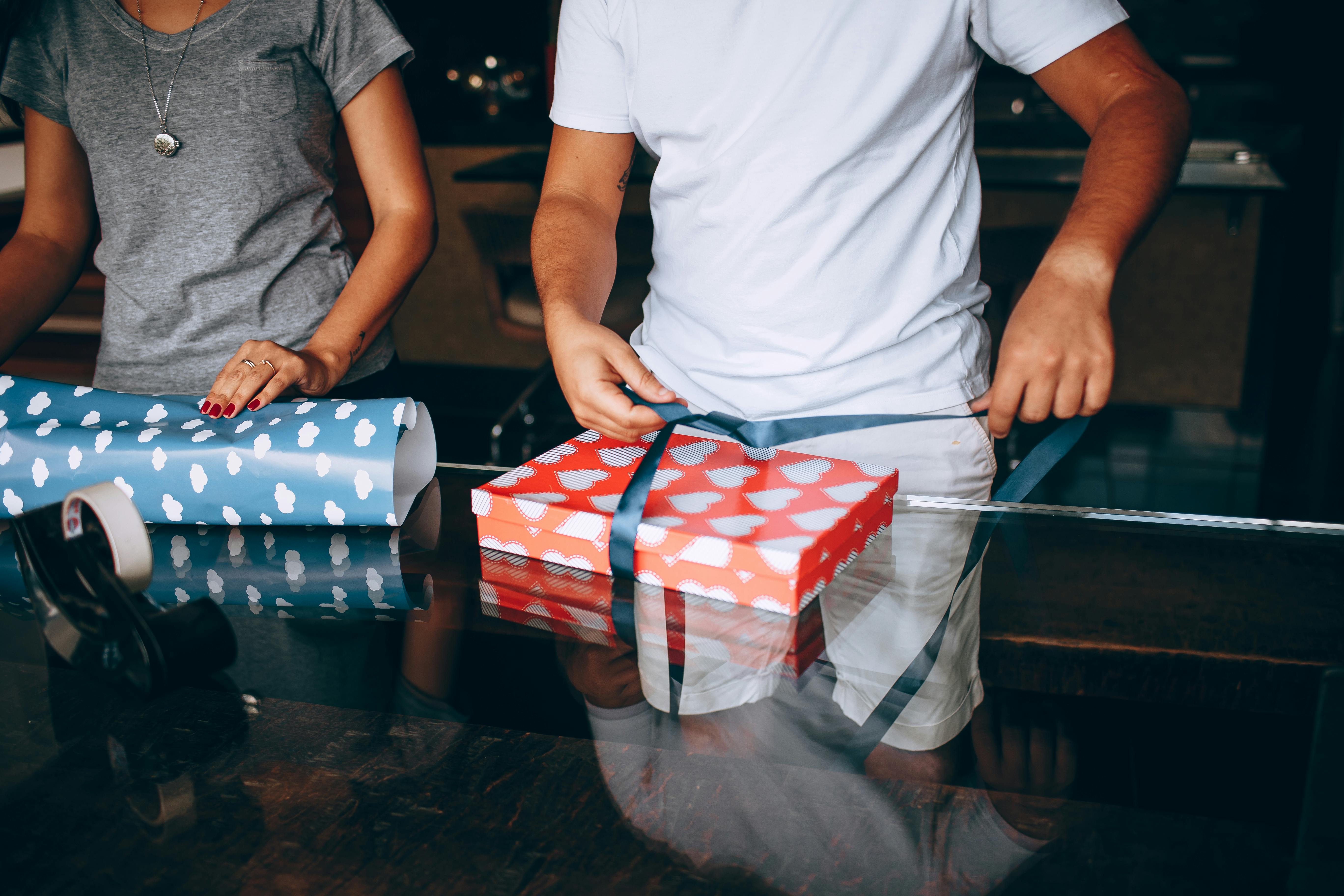 midsection of a young couple wrapping christmas presents