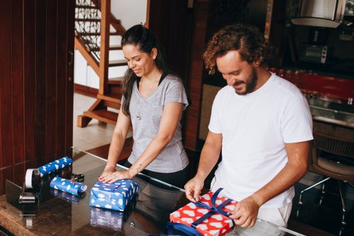 Free A happy couple wrapping presents together at home, showcasing joy and togetherness. Stock Photo