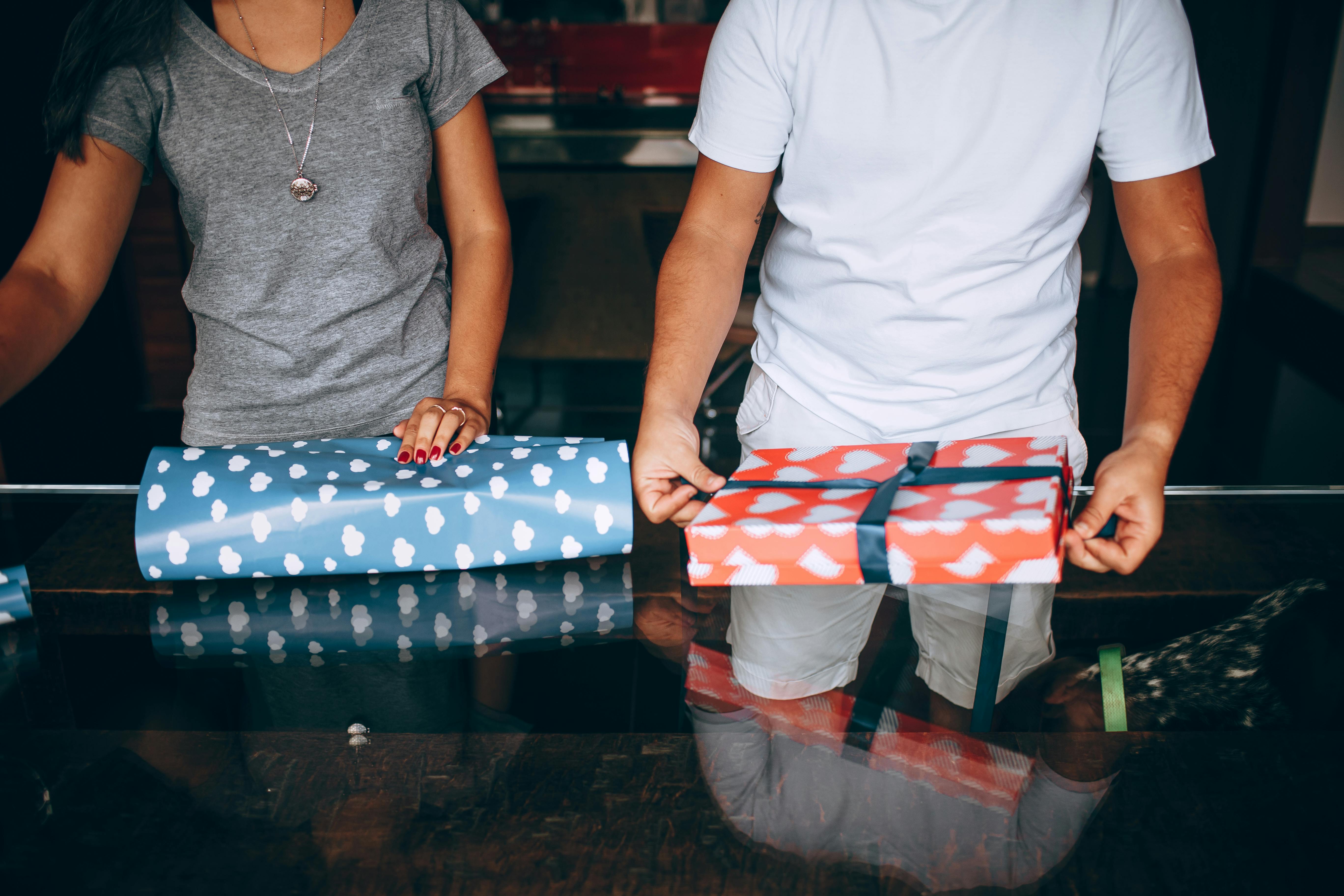 midsection of a young couple wrapping christmas presents