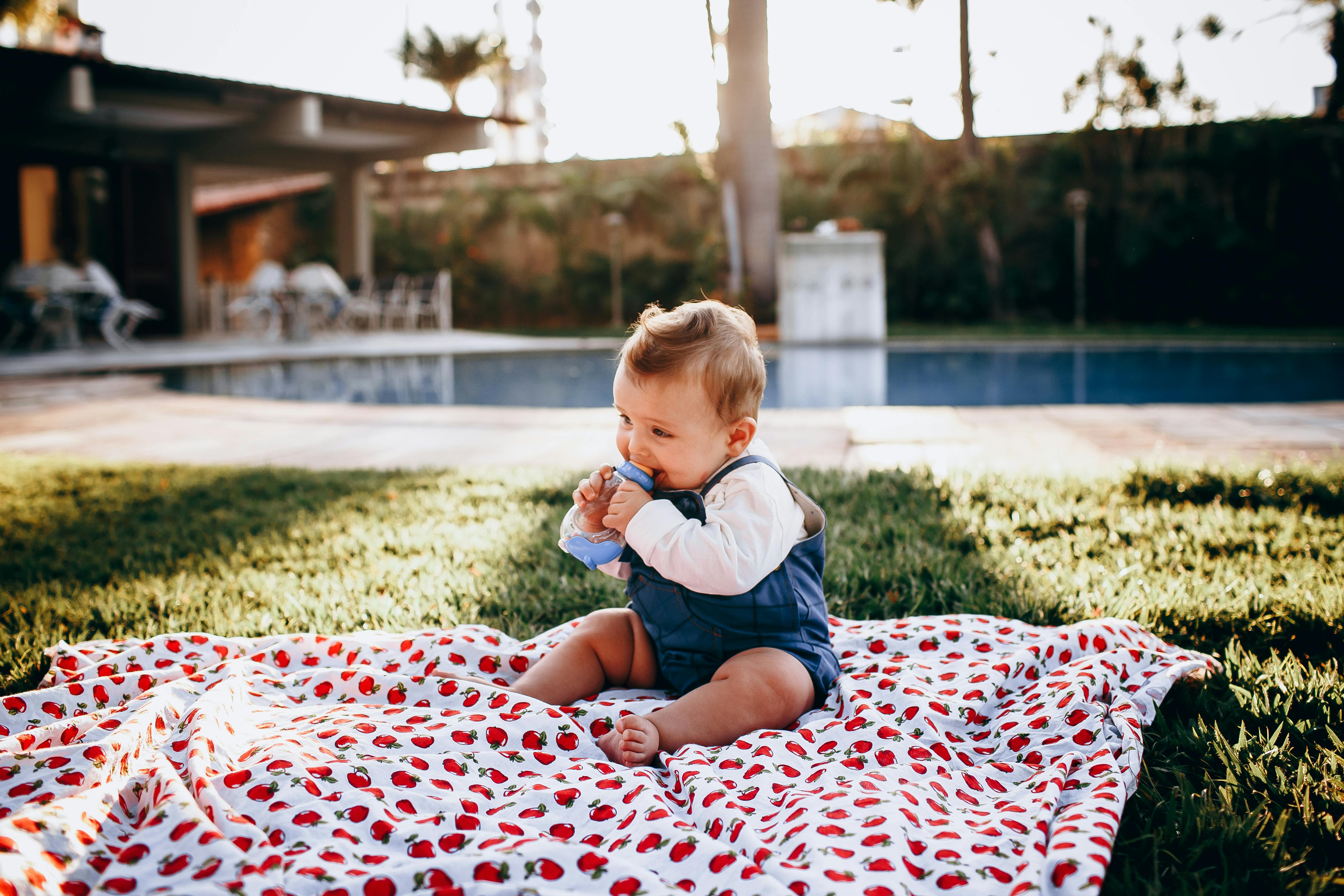 portrait of a cute baby sitting outdoors on a blanket