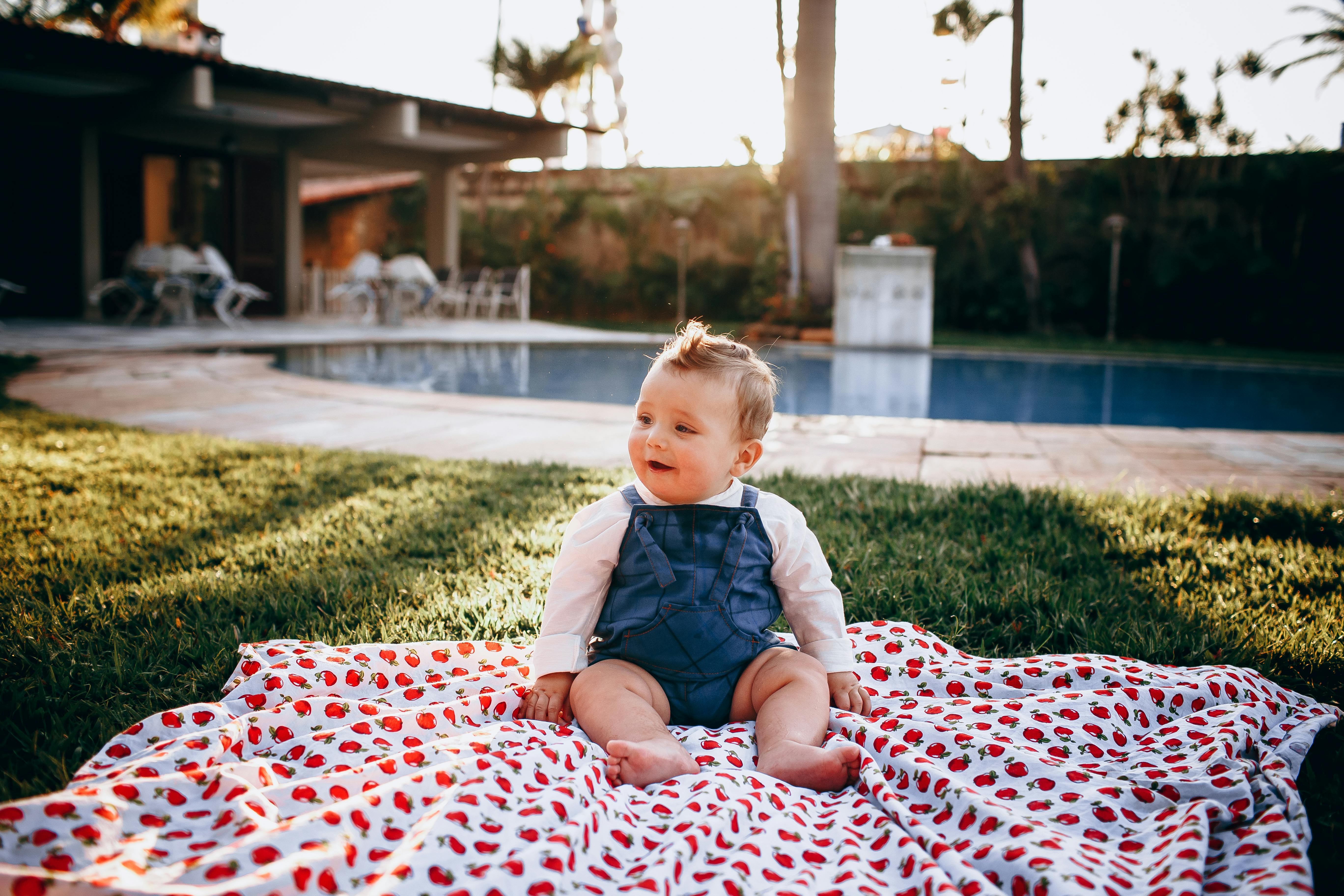 a baby sitting on a blanket in a garden