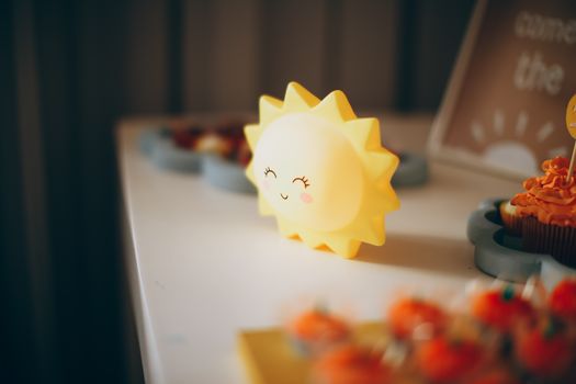 Bright and cheerful sun-shaped decoration alongside colorful cupcakes indoors.