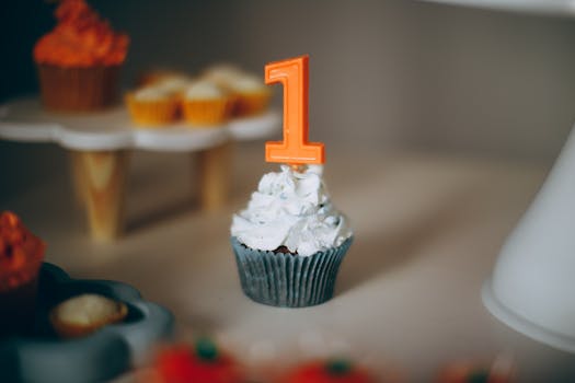 Blue cupcake with white frosting and orange number 1 candle, ideal for a first birthday celebration.