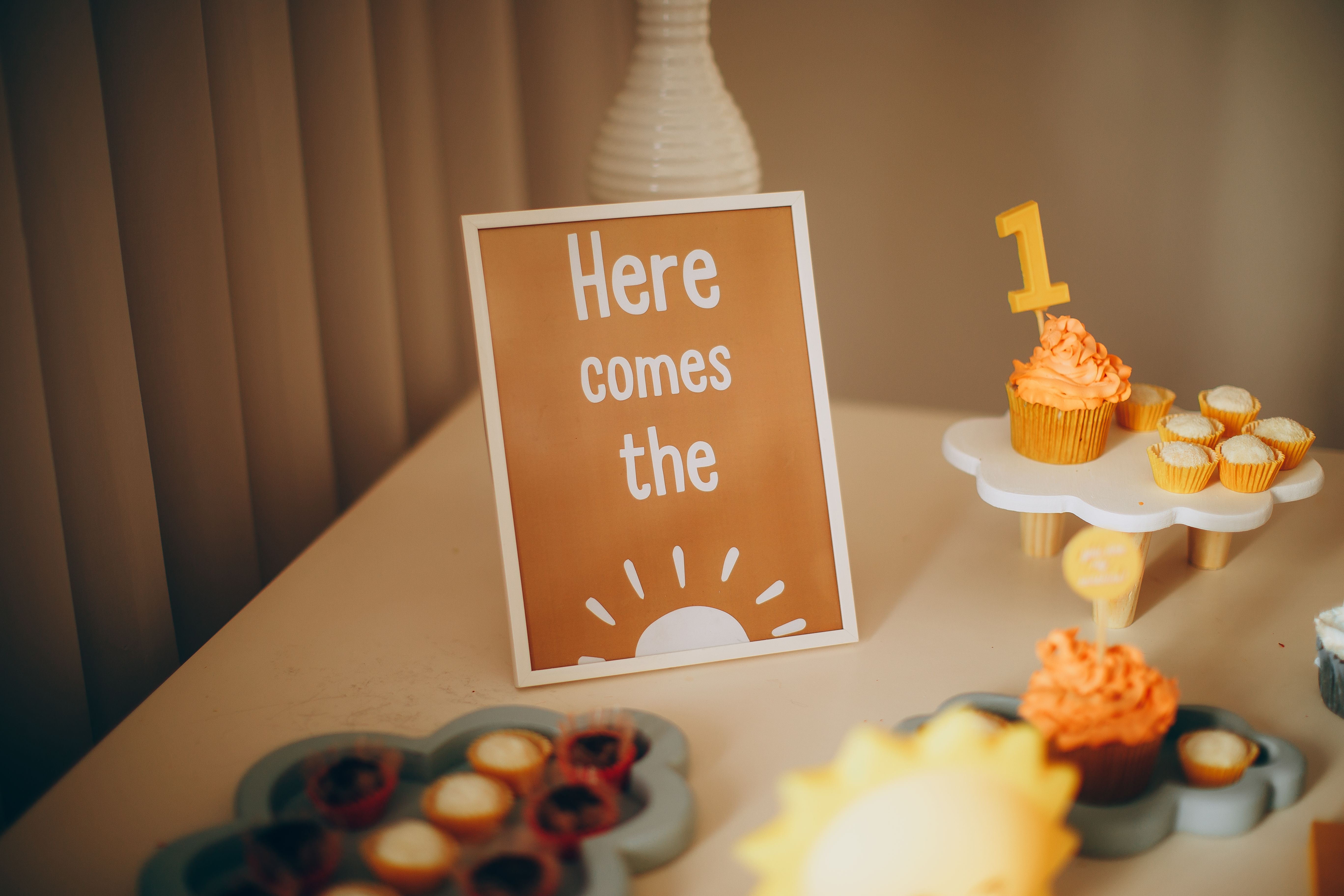 Celebratory setup of cupcakes and decorative sign at a first birthday party.