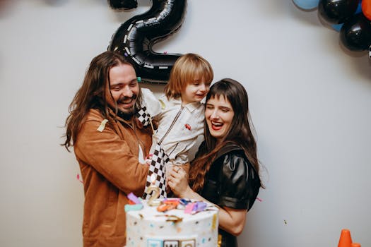 Joyful family celebrating their son's second birthday with smiles and a cake indoors.