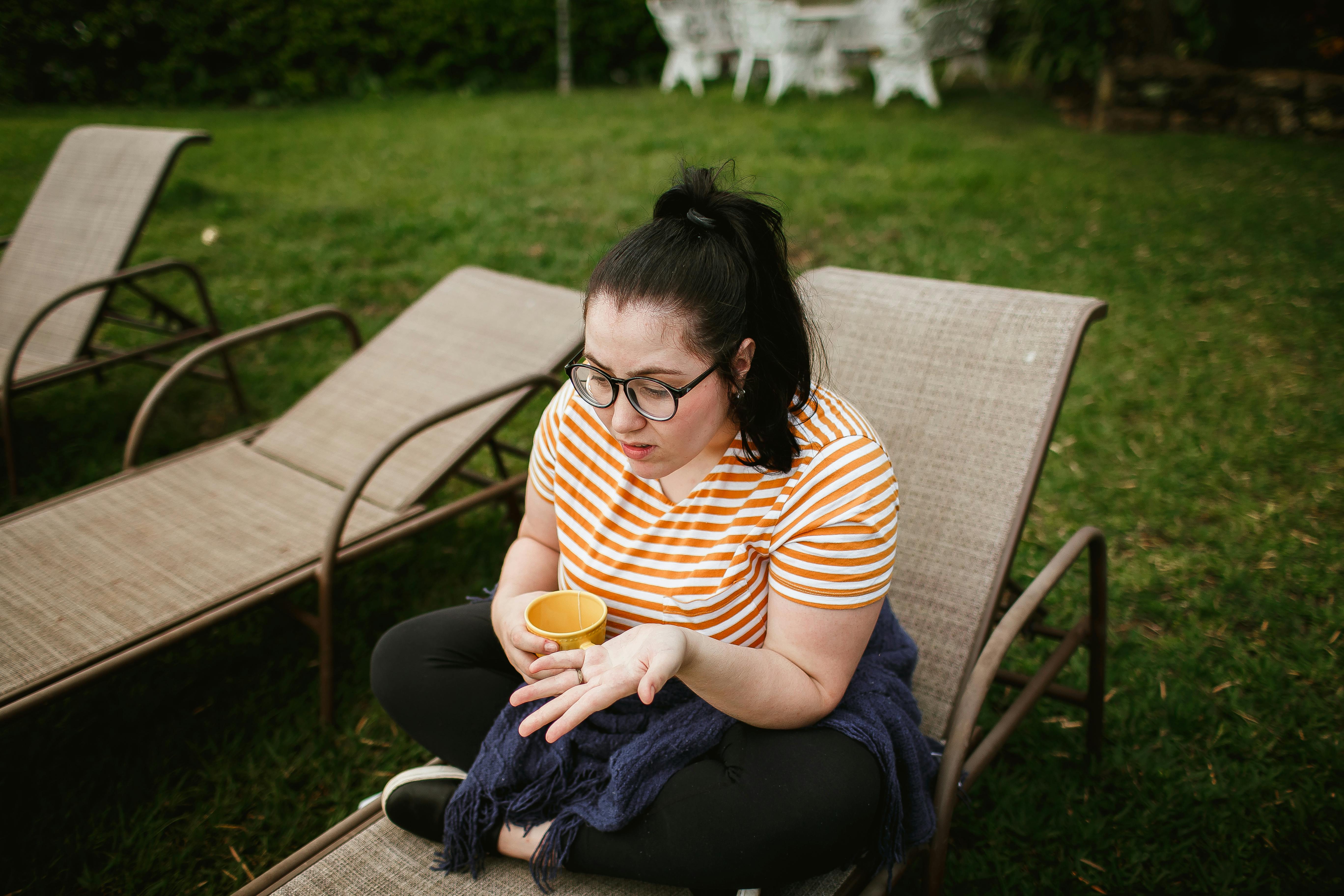 a woman sitting on a sun lounger and holding a cup