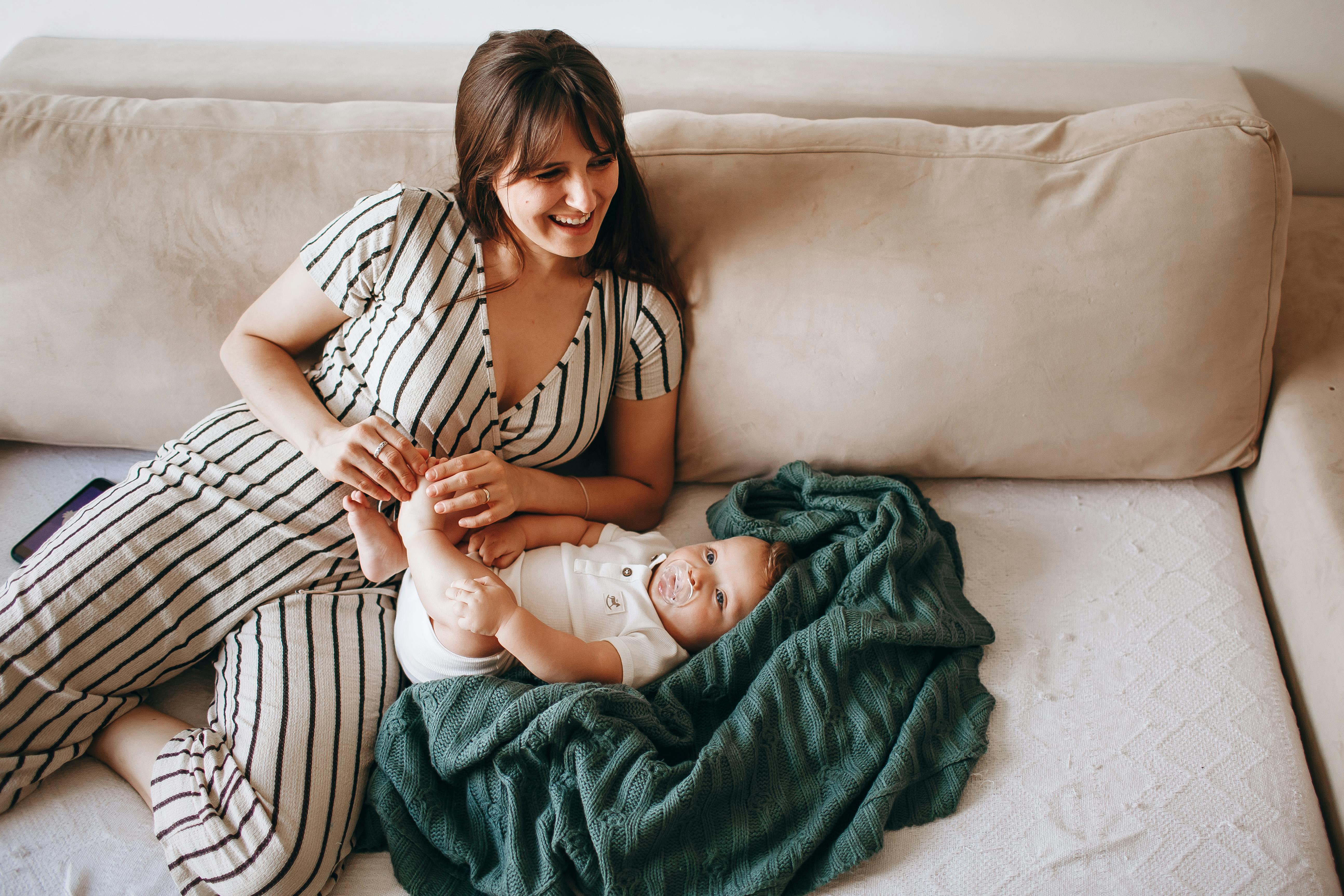 brunette woman smiling sitting on sofa with her infant child