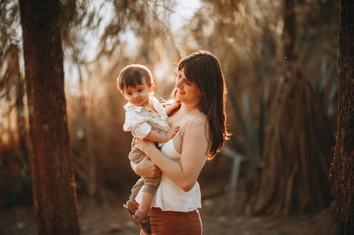 Free A mother lovingly holds her child in an outdoor setting on a sunny day. Stock Photo