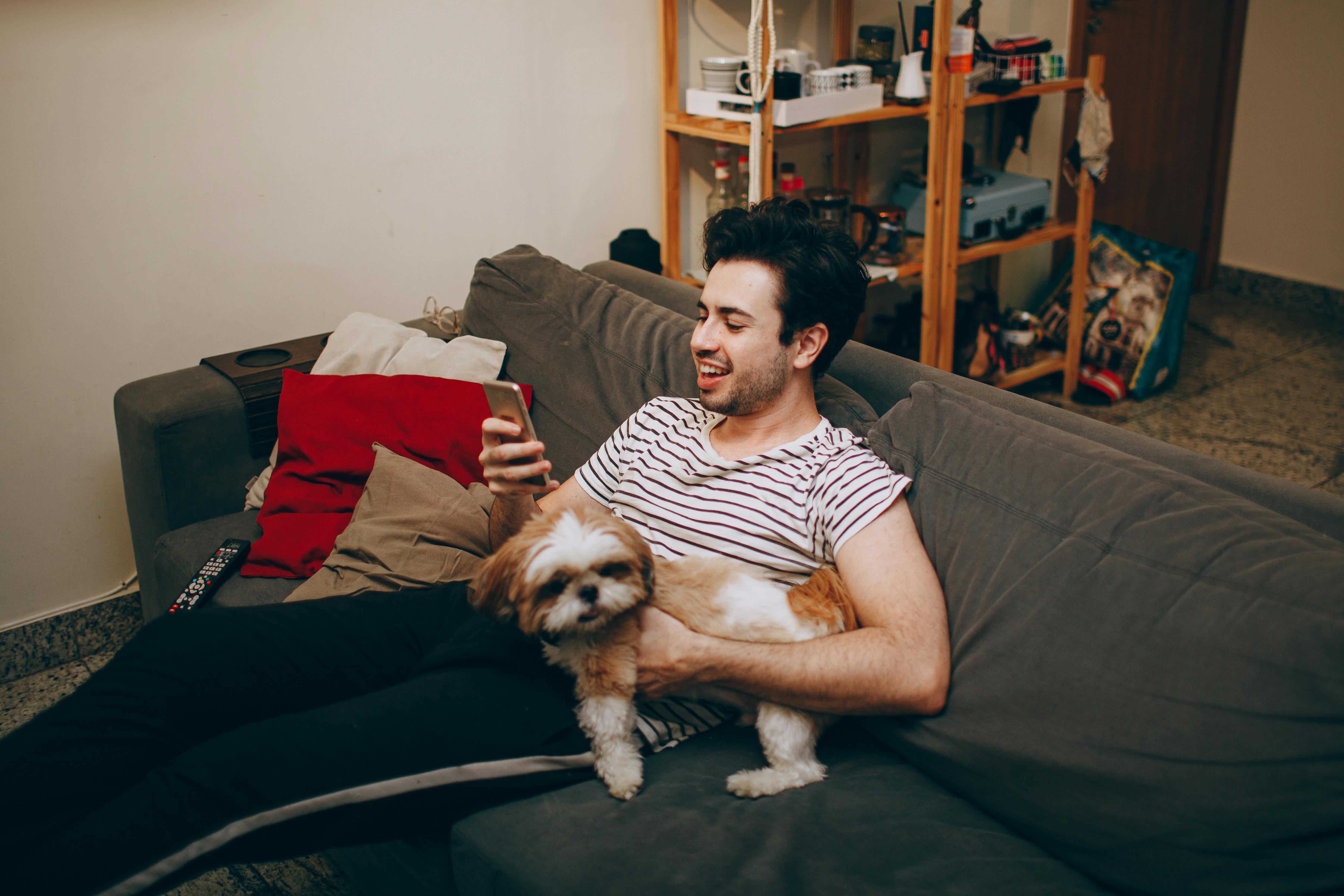 A man sitting on a couch with a dog