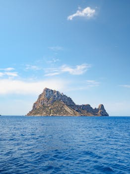 Breathtaking view of Es Vedra island with clear blue skies and ocean in Ibiza, Spain. Perfect for travel inspiration.