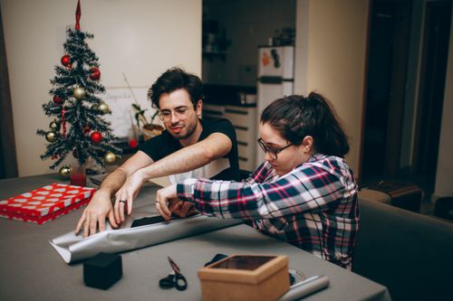 Free A couple enjoying togetherness while wrapping Christmas presents in a cozy indoor setting. Stock Photo