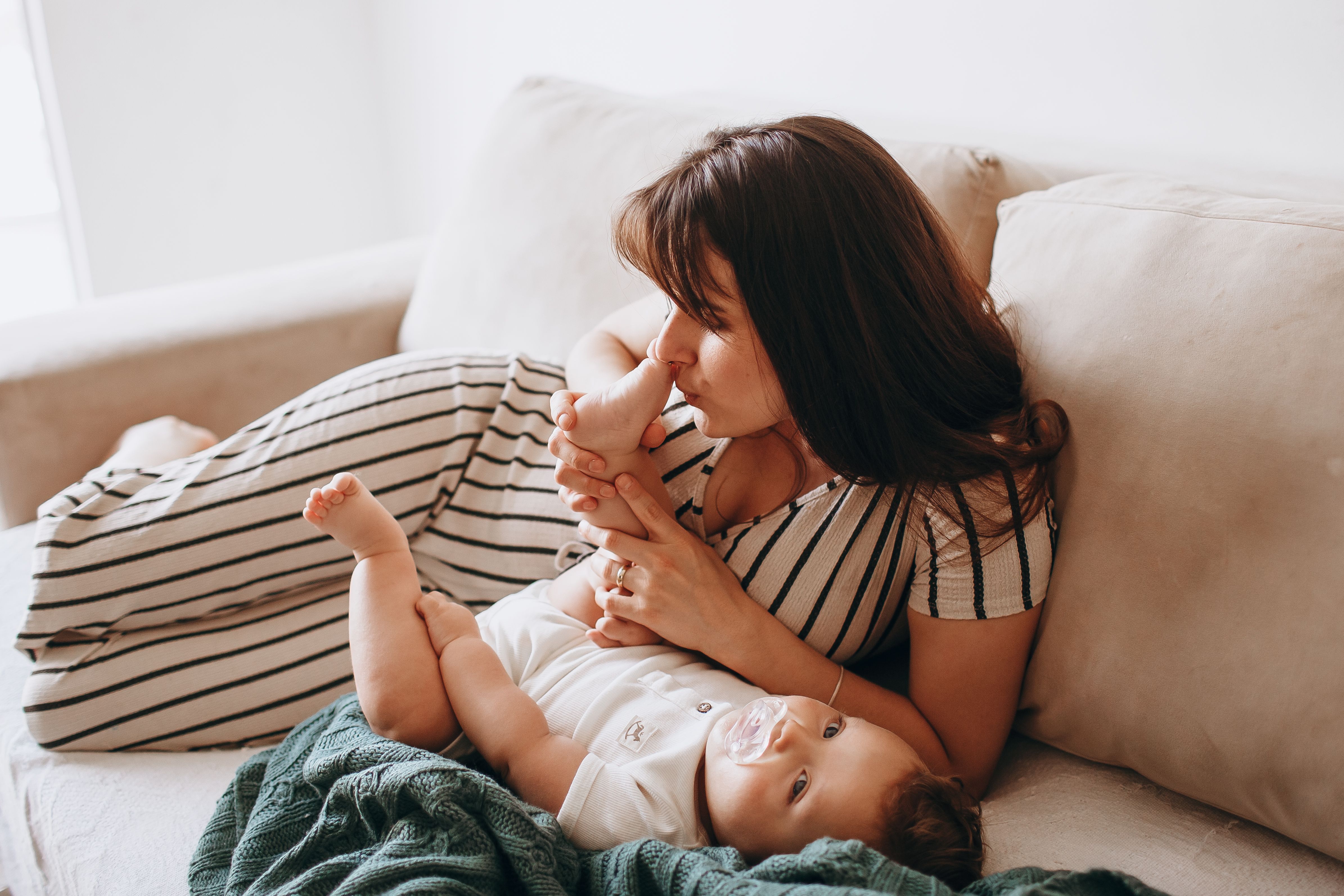 Warm portrait of a mother lovingly interacting with her baby on a cozy couch indoors.