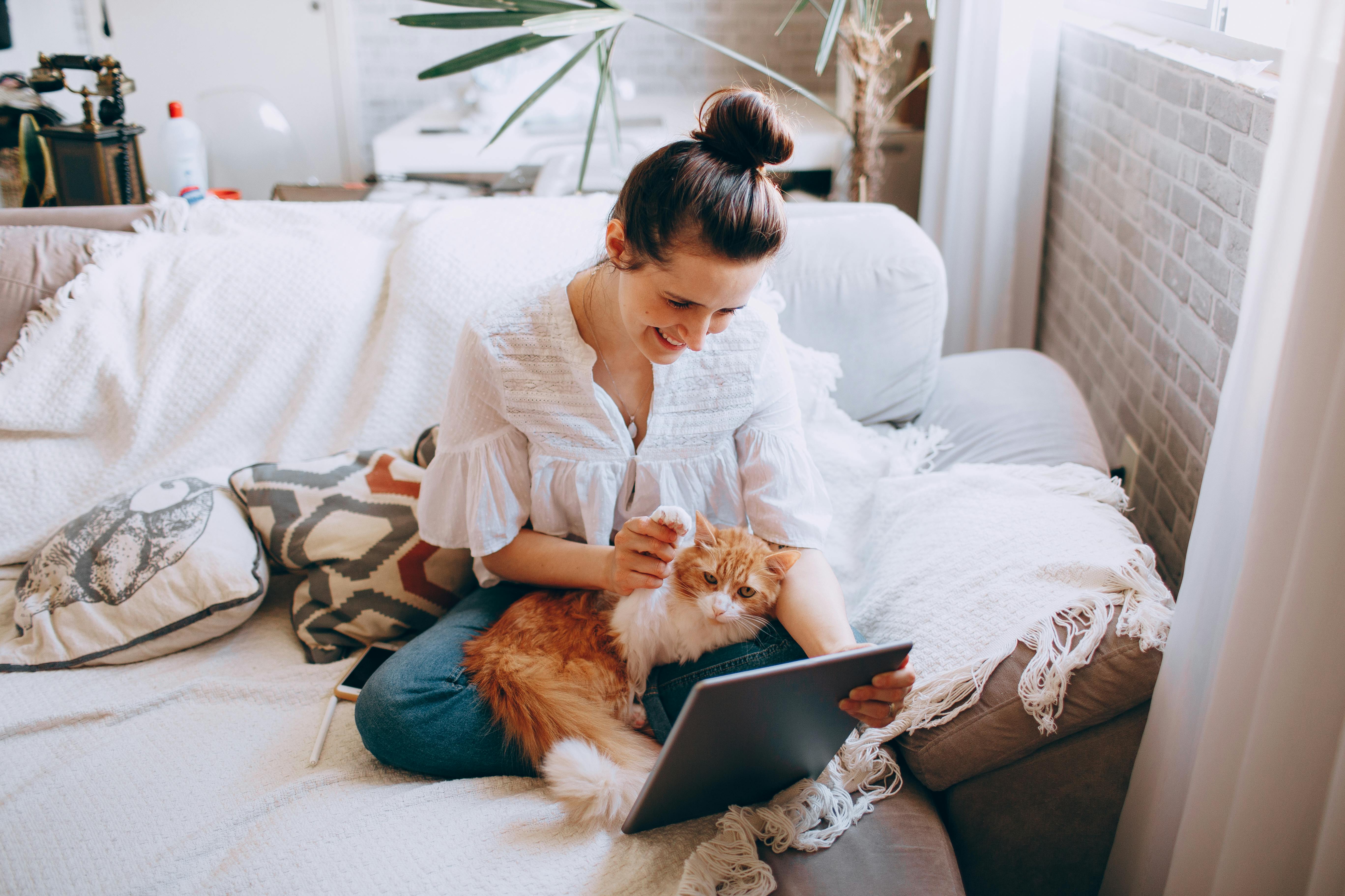Woman Sitting with Cat and Tablet on Bed