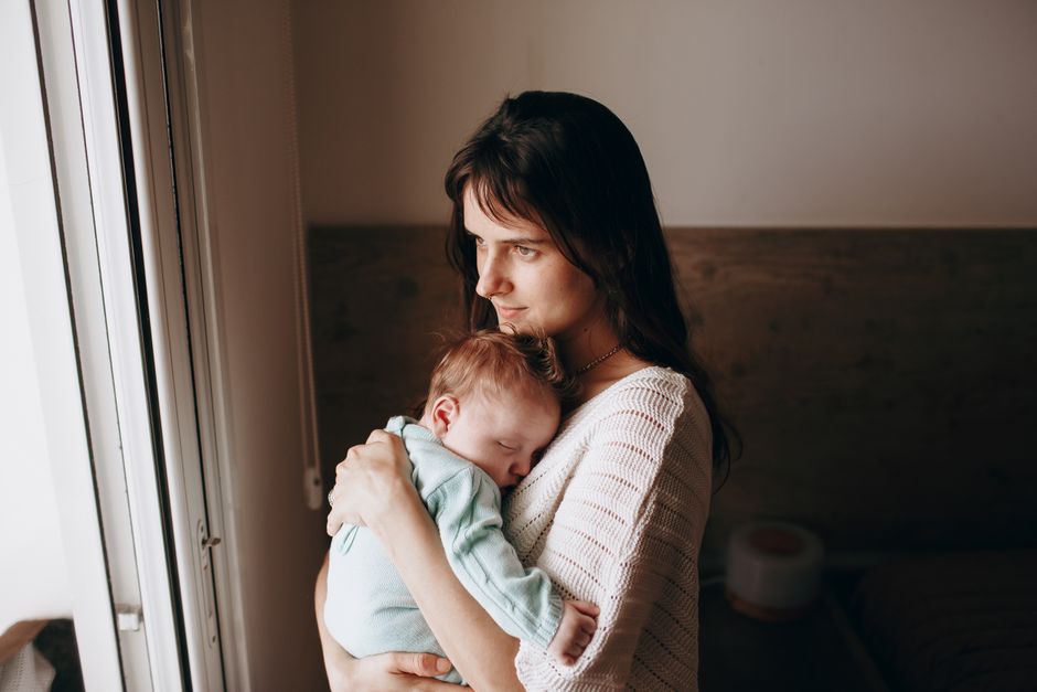 mother holding sleeping baby window