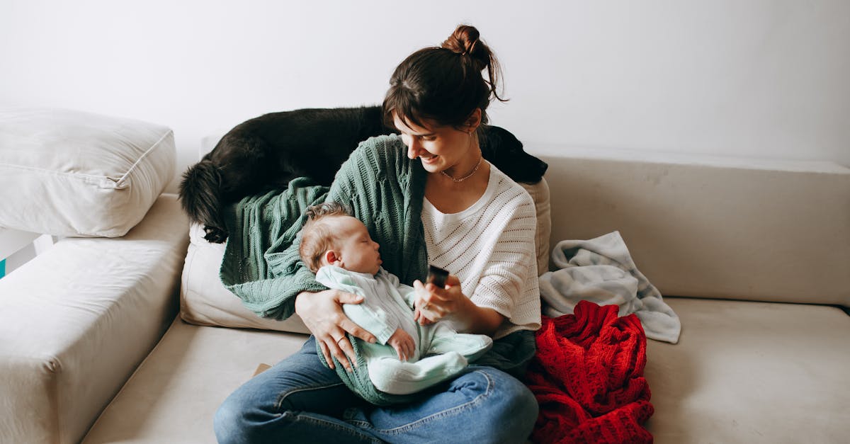 A woman sitting on a couch with a baby and a dog