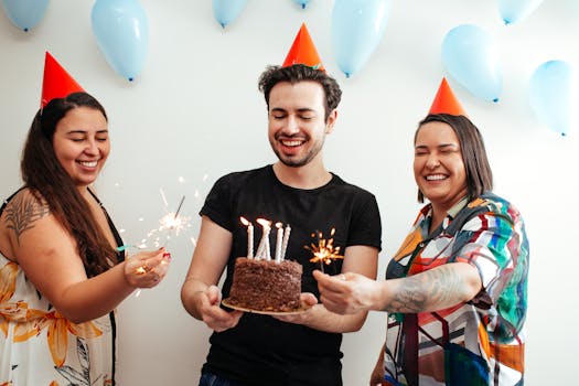 Happy group of friends celebrating a birthday indoors with cake and sparklers.