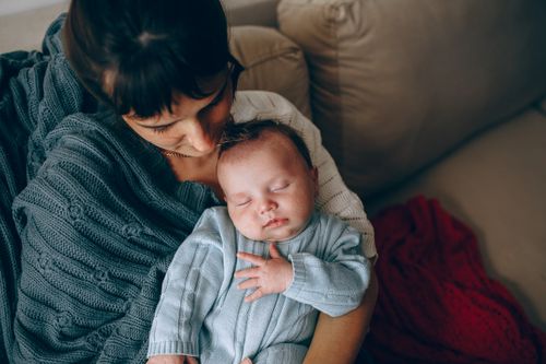 Free A tender moment between a mother and her sleeping baby in a cozy indoor setting. Stock Photo