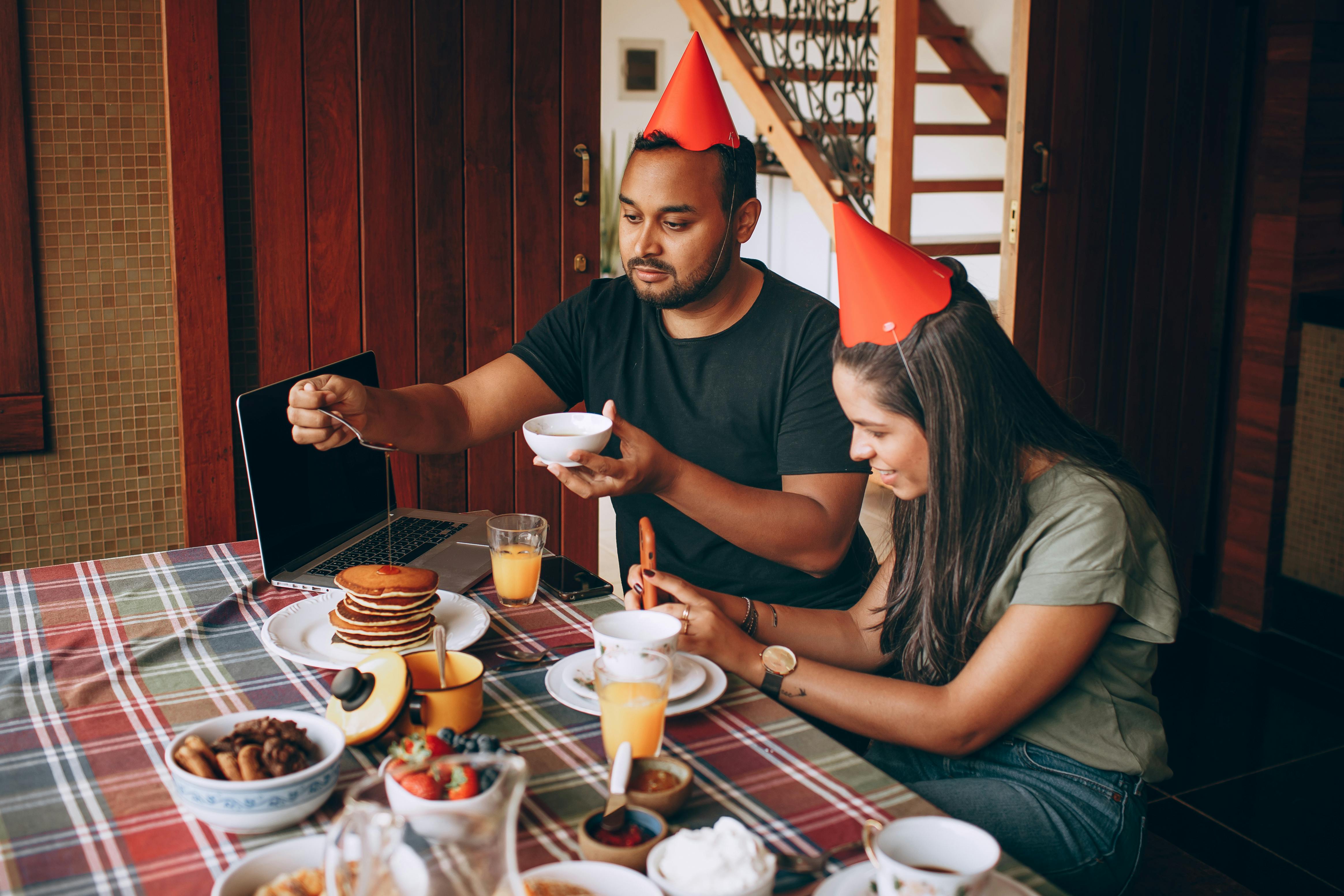 woman and man sitting in party hats at table