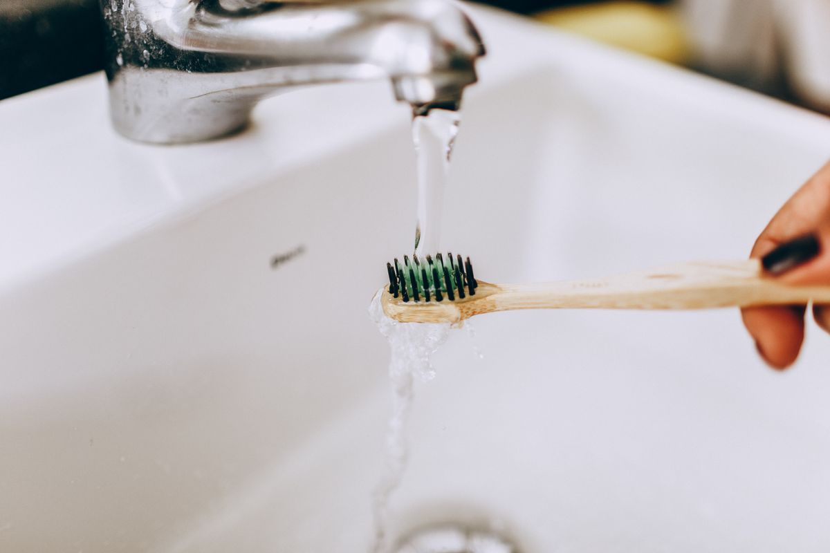 Toothbrush being rinsed under running water, illustrating a wet-use brush environment