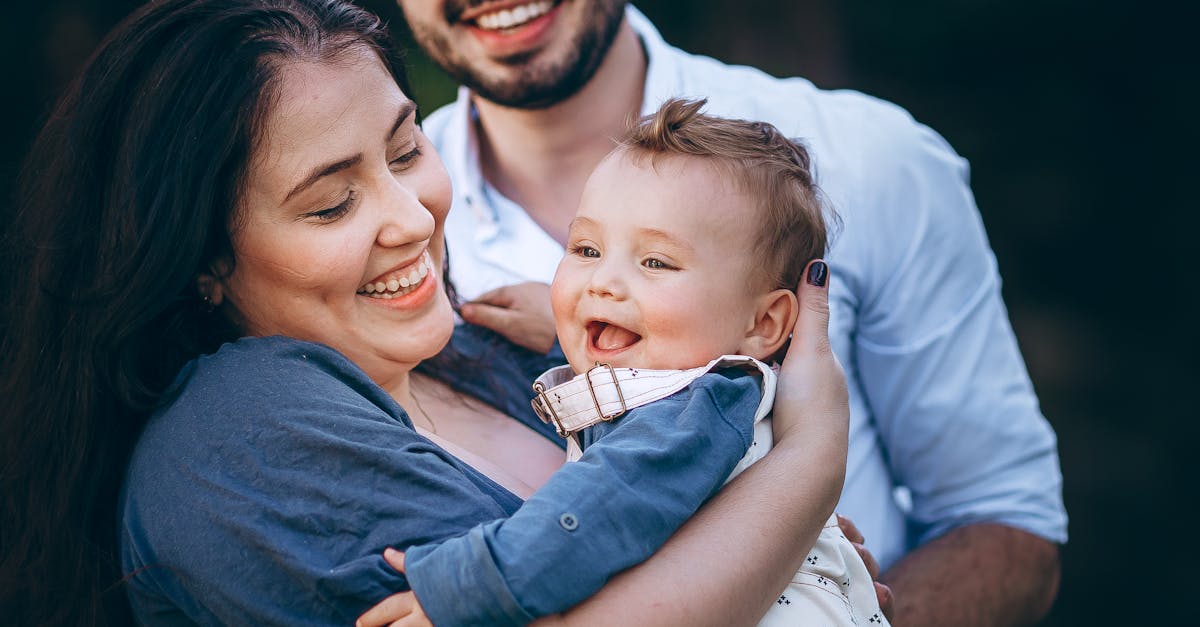 A family is smiling while holding a baby