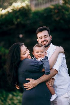 Smiling family embracing in a park, capturing love and happiness outdoors.