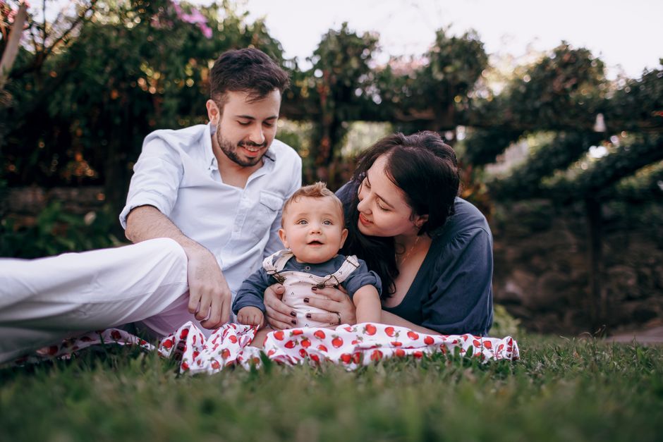 A young family with a baby enjoys a relaxing outdoor picnic on a warm sunny day, surrounded by nature.