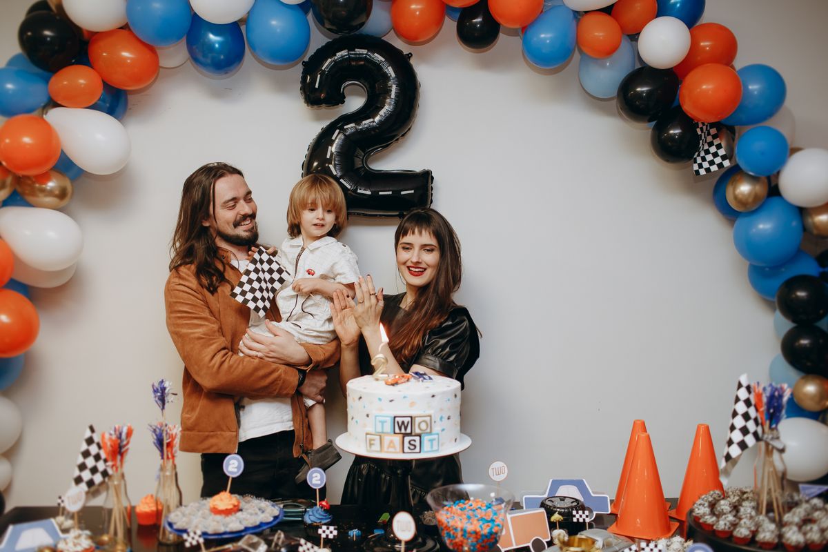 A cheerful family celebrates a child's second birthday with a colorful racing-themed party. Stock Photo.