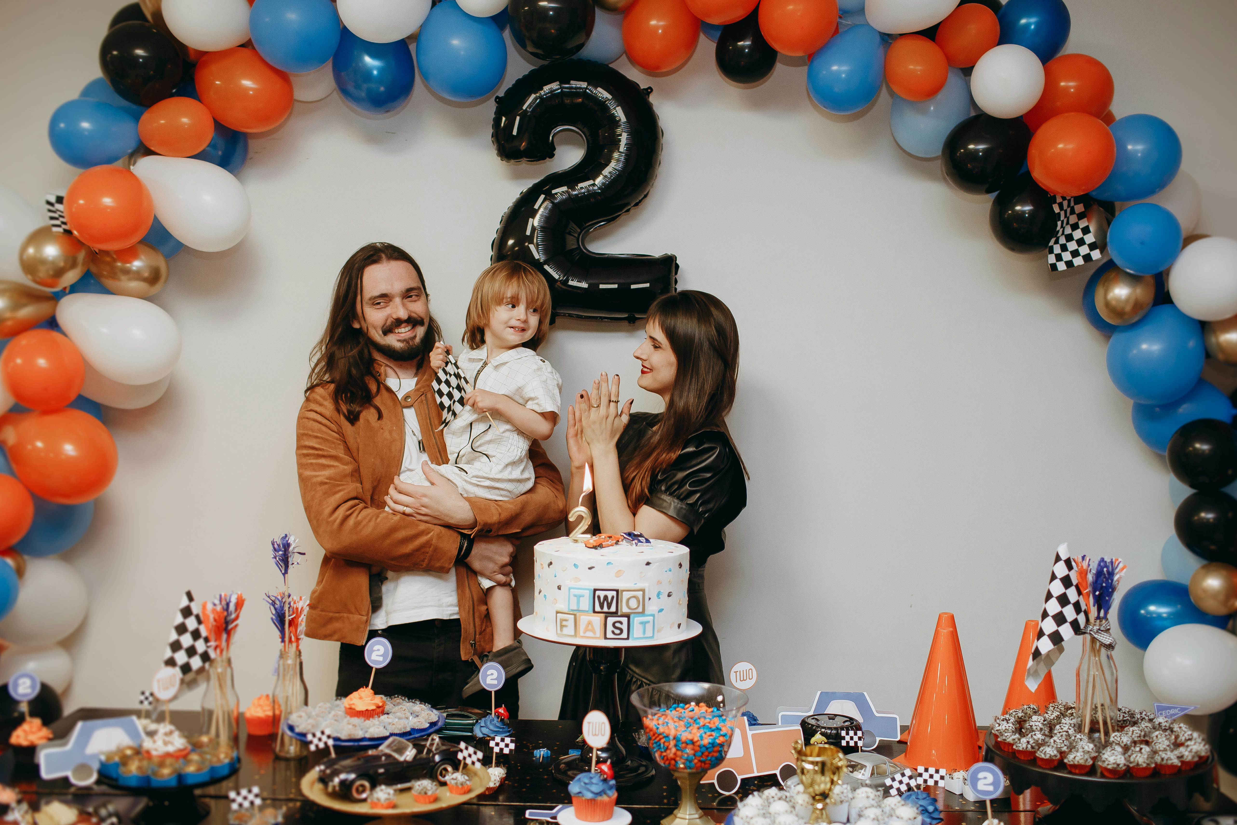 A family celebrating their second birthday with balloons and a cake