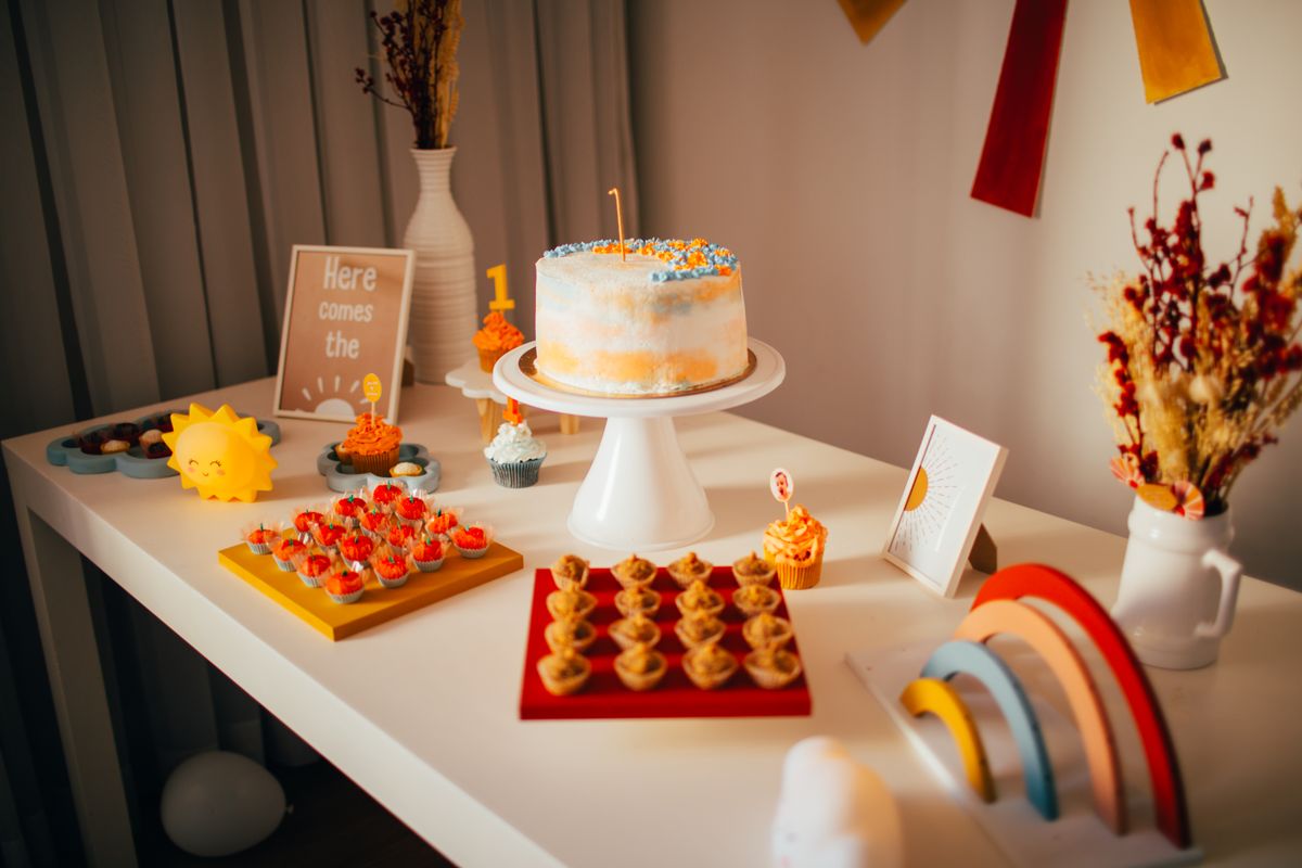 Colorful first birthday party table setup with cake and decorations indoors. Stock Photo.