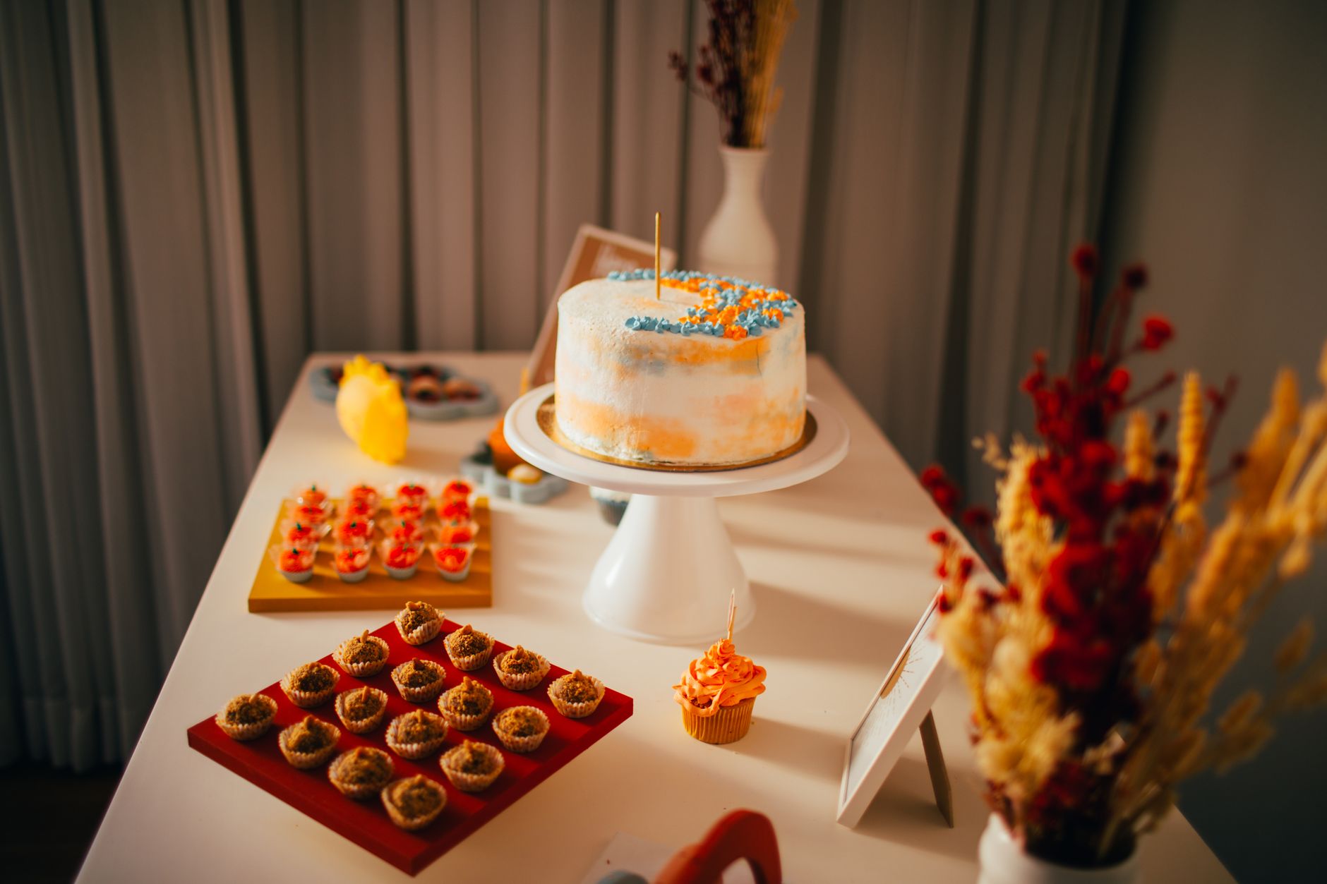 A beautifully decorated cake and desserts on an elegant indoor table setup.