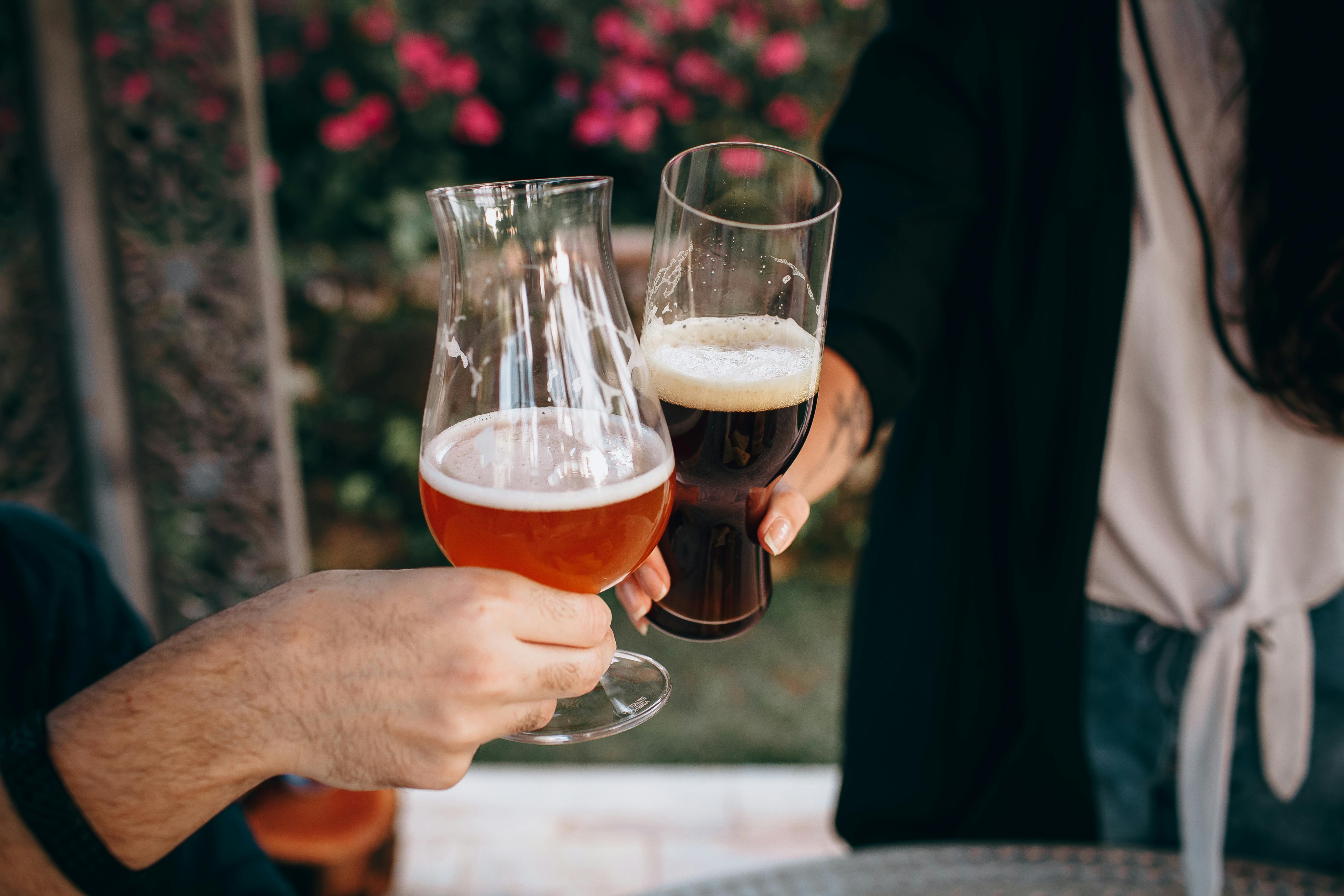 Two people clinking beer glasses at an outdoor summer party