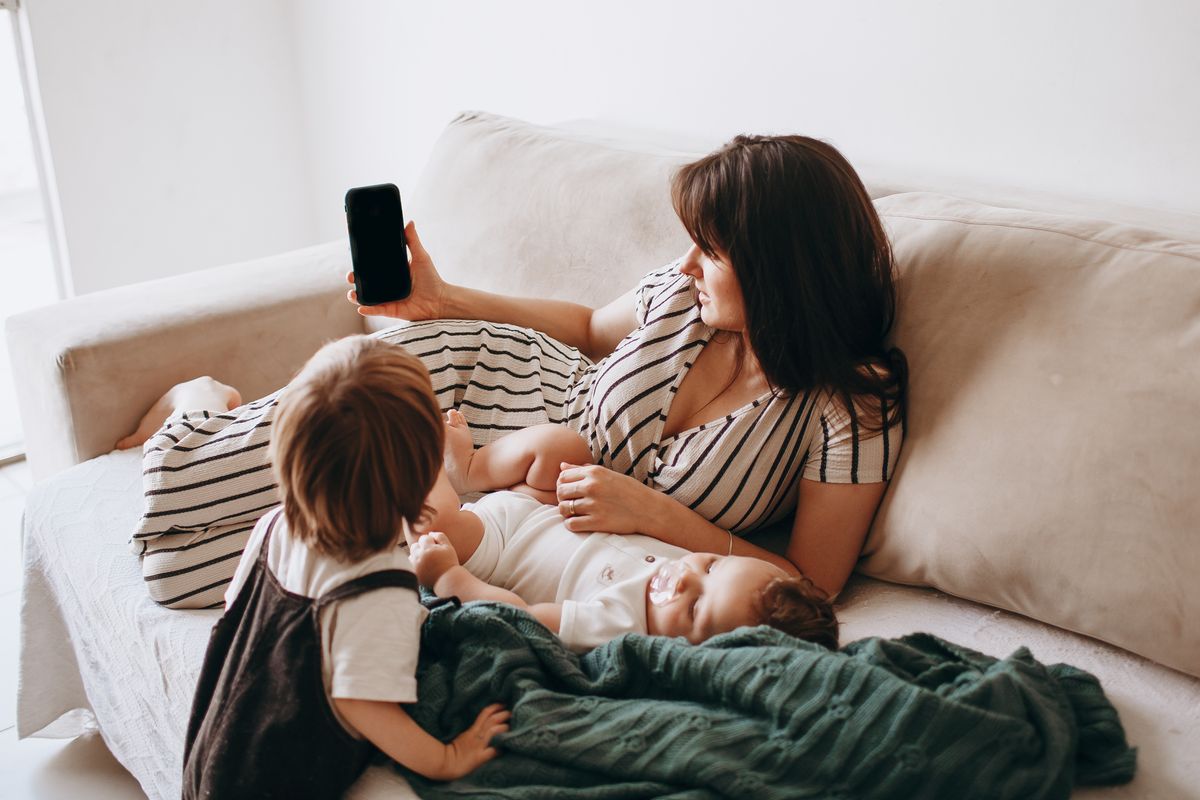Mother and children using a smartphone together in a living room