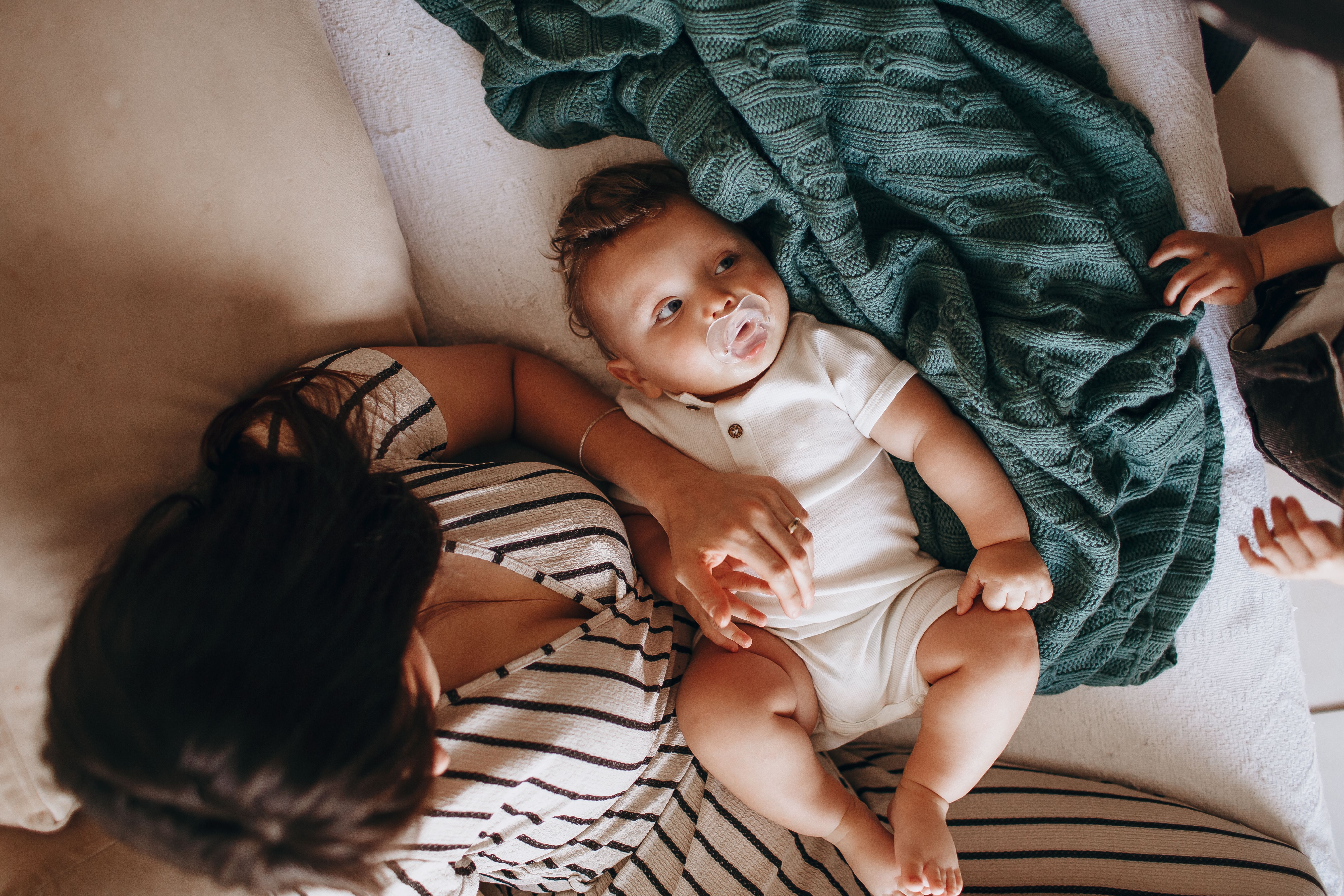 A mother and her baby share a tender moment while resting on a cozy bed at home.