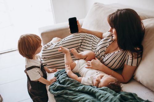 Free A mother enjoying time with her children on a comfortable couch, creating a warm, family atmosphere. Stock Photo