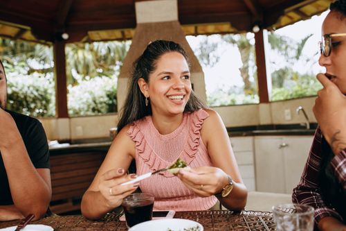 Free Friends sharing a meal in an outdoor gazebo, enjoying a relaxed and sunny day. Stock Photo