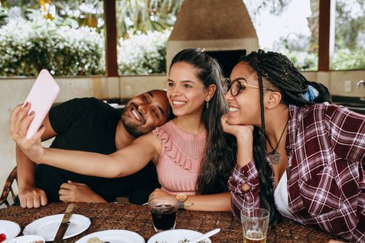 Group of friends smiling and taking a selfie during an outdoor gathering.