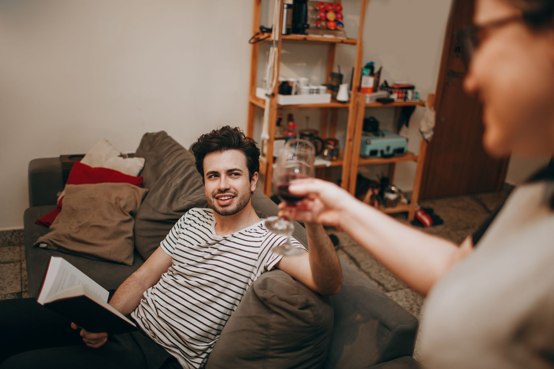 A relaxed indoor moment with friends, enjoying wine and conversation on a comfortable sofa.