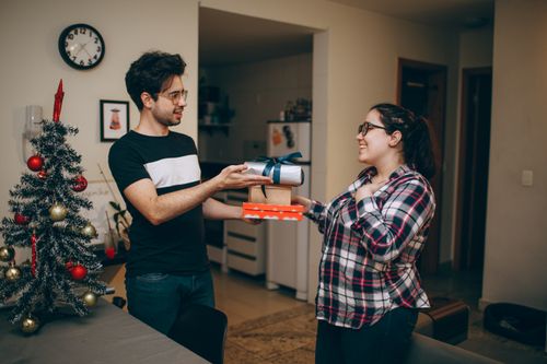 Free Happy couple exchanging Christmas presents in a cozy home interior. Stock Photo