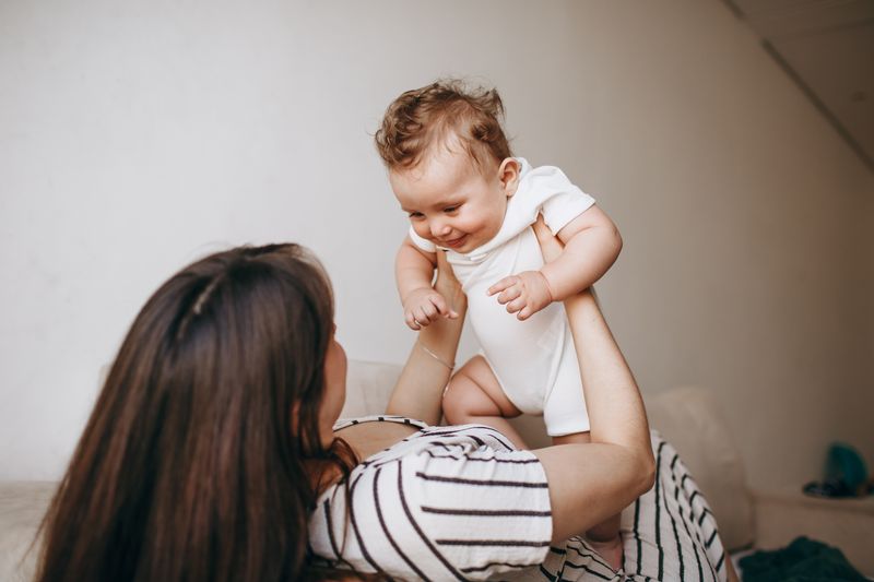 Mutter hebt ihr lachendes Baby in die Höhe