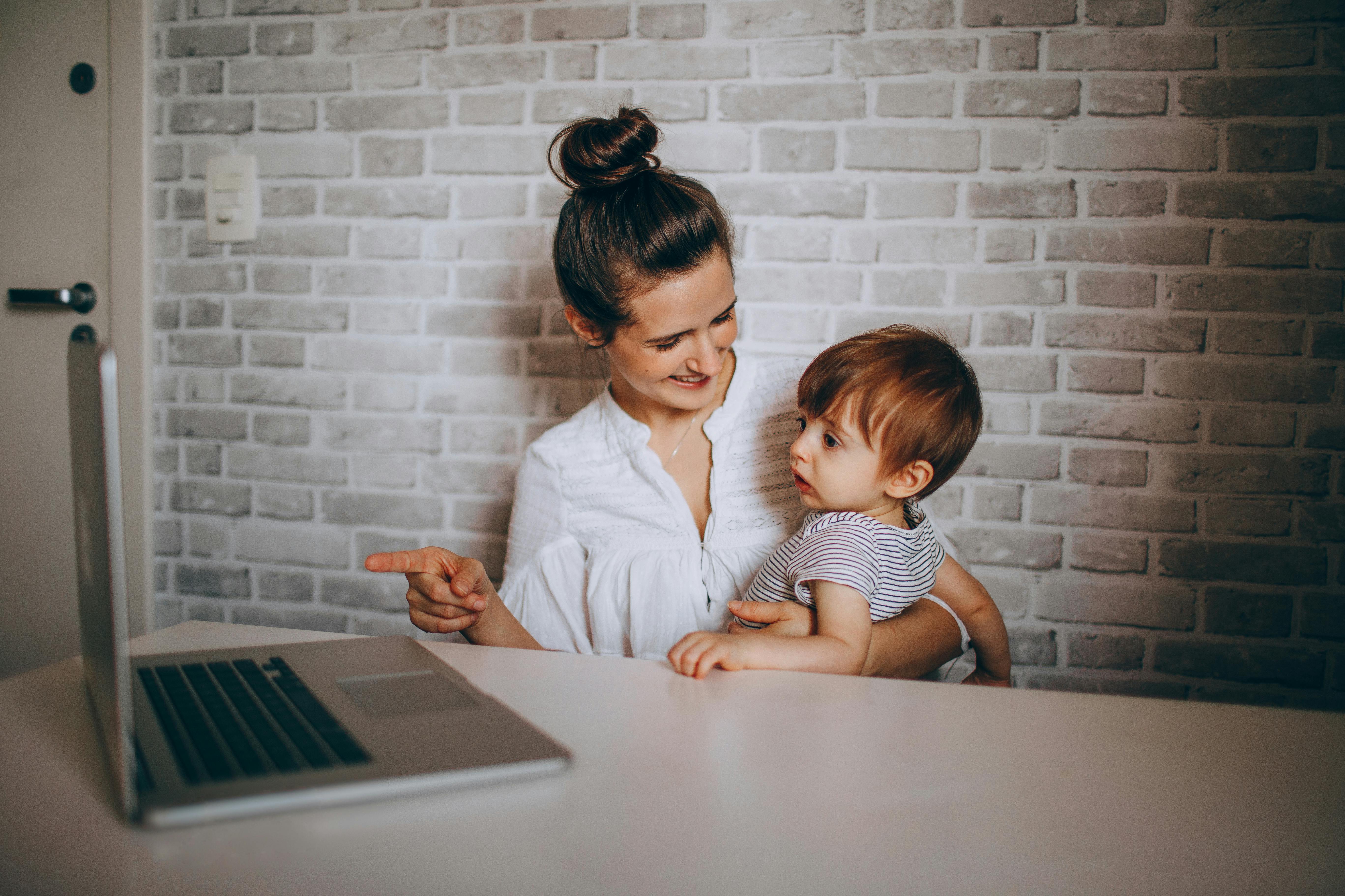 woman showing laptop to a boy