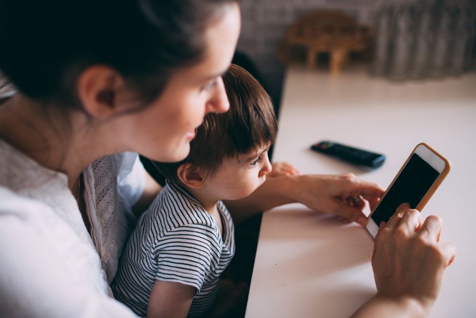 Baby Brezza Formula Pro Advanced vs Manual Bottle Prep: Safety and Convenience Compared A mother and child bonding while using a smartphone at home.