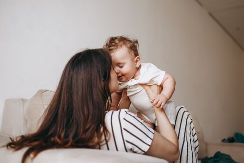 Free A heartwarming scene of a mother embracing her baby inside a cozy home. Stock Photo