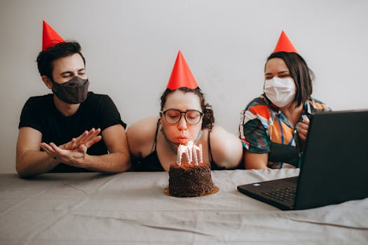 Masked friends celebrate a birthday virtually with cake and video call during COVID-19.