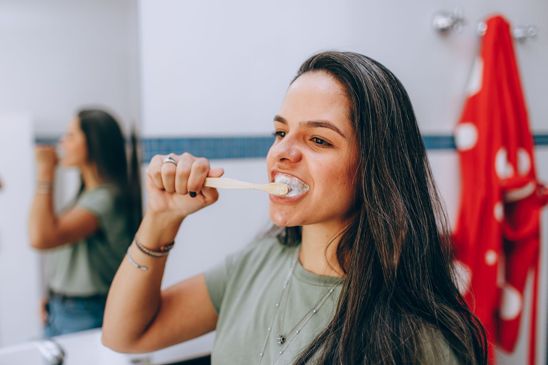 Woman brushing her teeth with a toothbrush in a bright bathroom during a daily oral care routine