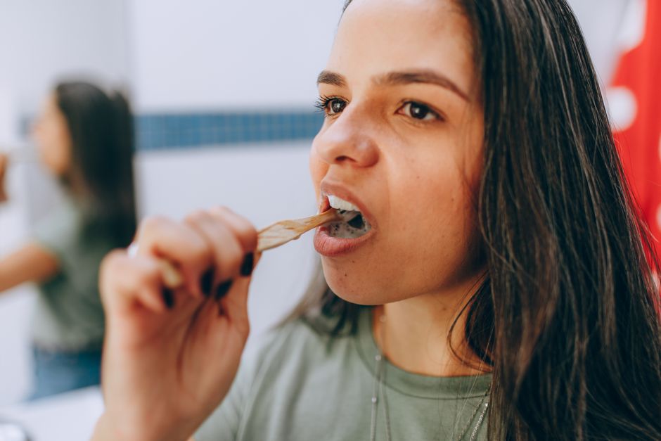 oral pH balance - A woman brushing her teeth with a toothbrush