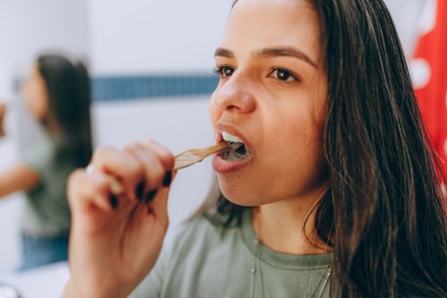 Free Young woman using a natural toothbrush for eco-friendly dental care, reflecting mindfulness and sustainability. Stock Photo