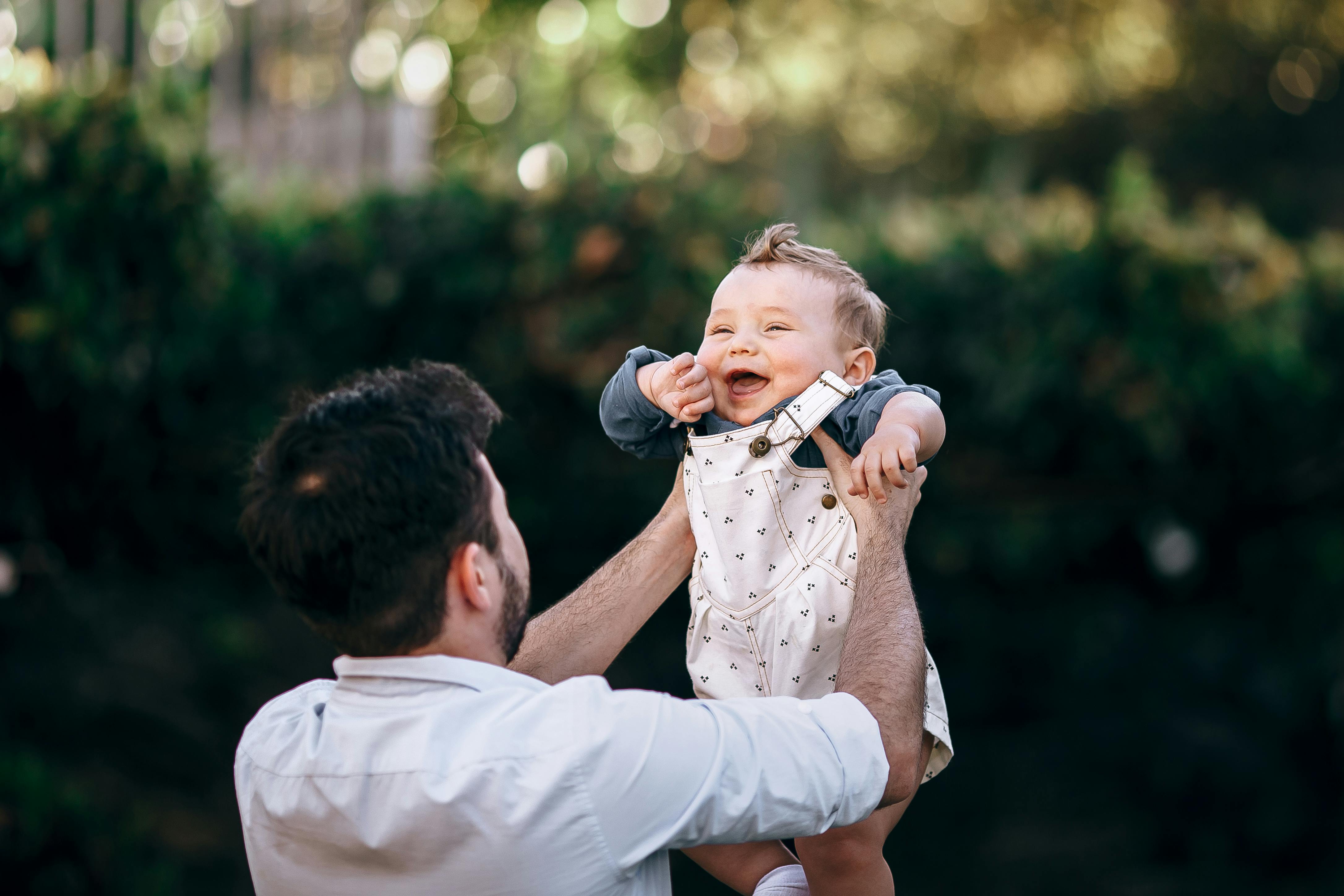 father standing and lifting newborn son