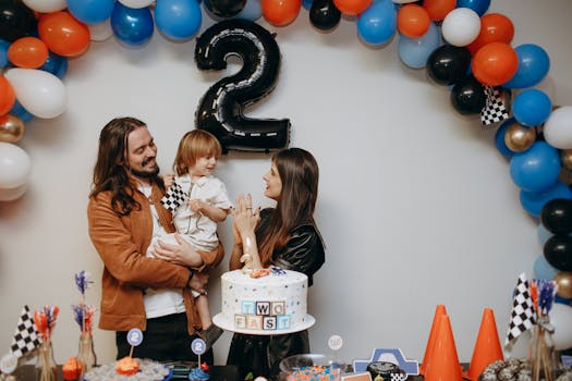 A joyful family celebrating a child's second birthday with balloons and themed decorations.